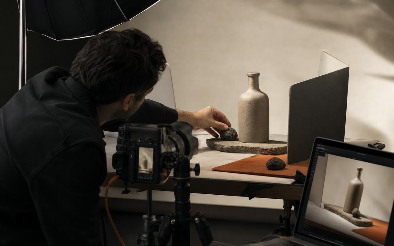 Product photographer composing an unbranded ceramic bottle in a controlled studio setup